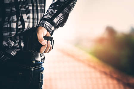 Robber pulls out a gun tucked in his blue jean. criminal and robbery concept.の写真素材