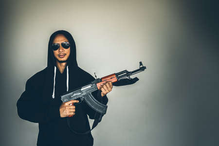 Robber holding a gun at abandoned building. Low key photo and selective focus. criminality concept.の写真素材