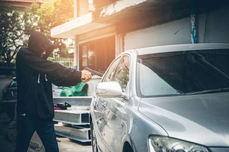 A robber dressed in black pointing a gun at a driver in a car. Car thief concept.の写真素材