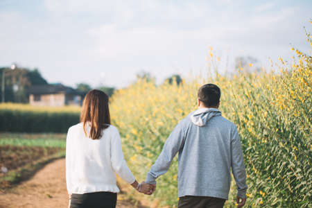 Young couple are happy and standing on a meadow in the morning on winter season. Green and yellow grass on background.の写真素材