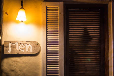 Public Men toilet sign on old wooden with light at night time.の写真素材