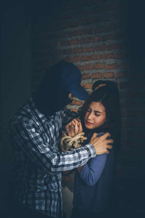 Sexual abuse with a terrorist attacking a scared woman in a dark place. Rape and Sexual abuse concept.の写真素材