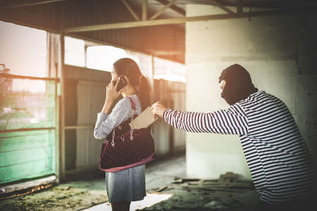 Thief stealing wallet from pocket women while her playing smart phone at side way. criminal and robbery for women concept.の写真素材