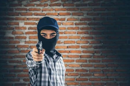 Robber holding a gun. Low key photo and selective focus. criminality concept.の写真素材
