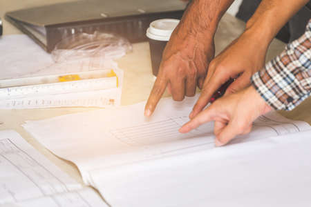 Foreman, labor and engineer as discussing about their project on table with safety helmet on old buildings in their job site.の写真素材