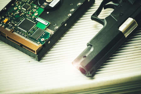 Computer hard drive and short gun put on a briefcase. Terrorist and hacker concept.の写真素材