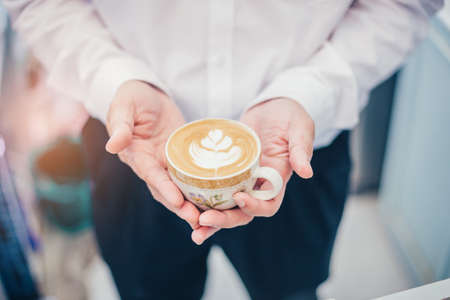 Barista holding cup of tulip latte art coffee in coffee shop.の写真素材
