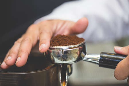 Hand of barista using tamper to press ground coffee into portafilter in cafe for prepare to make espresso coffee.の写真素材