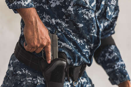 The soldier in the performance of tasks in camouflage holding a pistol with the hammer cocked takes aim for shot. War zone. Secret mission concept.の写真素材