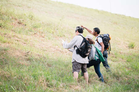 Group of backpacking hikers going to mountain top and navigating by map. Backpackers or Hikers travel concept. Selective focus.の写真素材