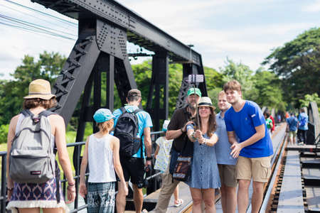 KANCHANABURI, THAILAND - JULY 22 2017: Happy traveling family taking selfies with smartphone on railway bridge, sunny summer colors, romantic mood.のeditorial素材