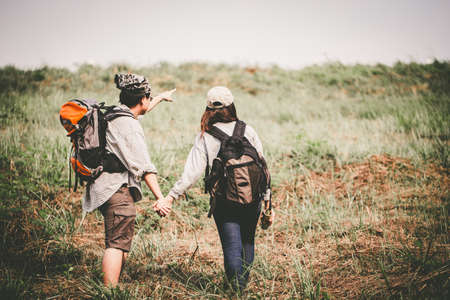 Couple of backpacking hikers going to mountain top and navigating by map paper. Backpackers or Hikers travel concept. Selective focus and vintage tone.の写真素材