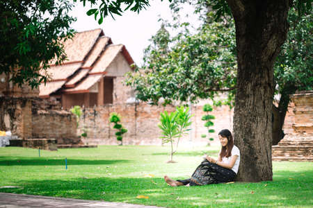 young woman sitting under a tree and writing her diary. women with natural conception.の写真素材