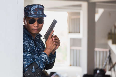 The soldier in the performance of tasks in camouflage holding a pistol with the hammer cocked takes aim for shot. War zone. Secret mission concept.の写真素材