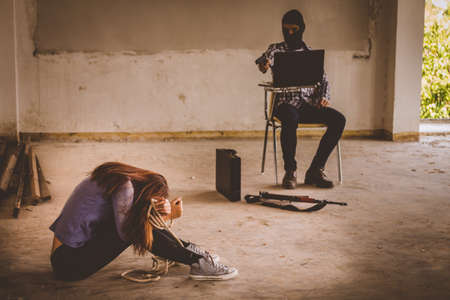 Man in hoodie robbing and threatening with gun to frightened young woman. criminal and robbery for woman concept.の写真素材