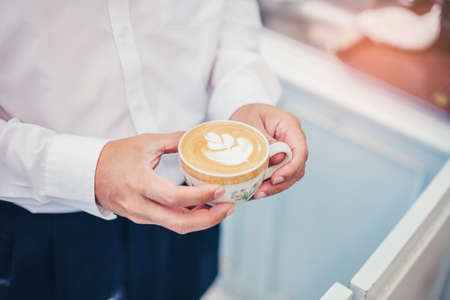 Barista holding cup of tulip latte art coffee in coffee shop.の写真素材