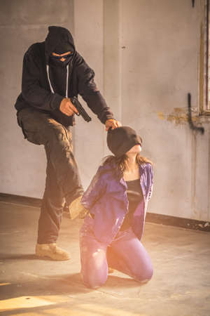 A terrorist man holding gun kidnapping young women for a hostage in abandoned building. Rape,...