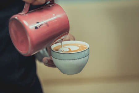Hand of barista pouring milk make coffee latte art with white cup in cofee shop. Tulips coffee latte art.の写真素材