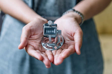 Concept of Happy New Year 2018 celebration. Hand of womam holding Number Hand Tally Counter stop at 2018 on white wooden table with copy space.の写真素材