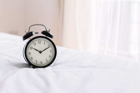 Retro alarm clock on bed in bedroom at morning. Use for alarm to wake up.