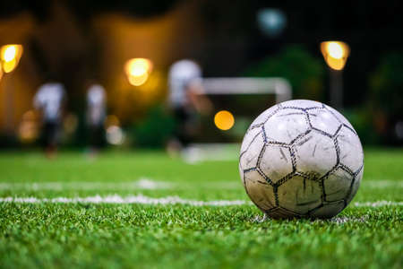 Old Soccer ball, Football on the grass line in soccer stadium at night with copy space and player with light background. goal,success concept.の写真素材