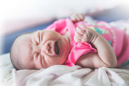 The infant is crying and lying on the bed.の写真素材