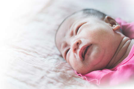 The infant is crying and lying on the bed.の写真素材