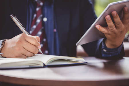Business planning concept. Businessman hand holding the pen and planning him business on notebook....