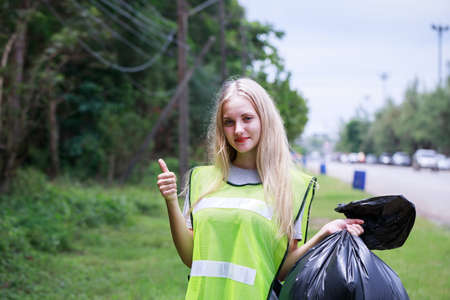 Volunteers, Caucasians are helping to pick up waste by garbage bags beside the road. CSR activity. Corporate Social Responsibility. Environmental problem. Environment dayの写真素材