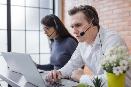 young women and man call center wear headset and working with laptop while consulting customers with online problems. support operator service business representative concept. online marketingの写真素材