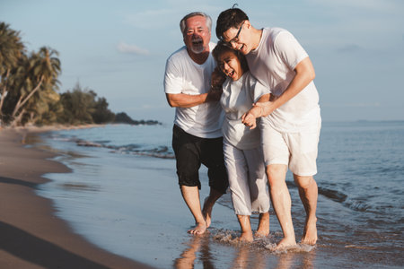 Asian senior couple and son walking on summer beach sunset. Travel leisure and activity after retirement on vacations and summer concept. Vacation and relaxation time of family.の写真素材