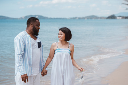 Romantic African American couple laughing and having fun together while walking on the beachの写真素材