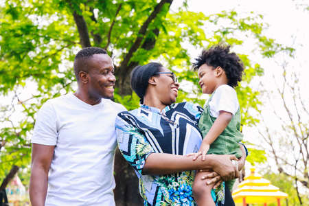 Portrait of African American family. Happy African American parent (Father, mother) and son are smiling together while standing in the park in the daytime in summer. Happy family concept.の写真素材