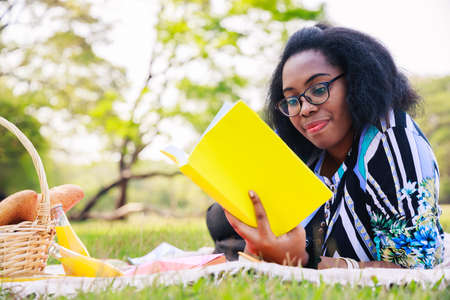 Happy young African American woman reading an interesting book. A cheerful African American woman in...