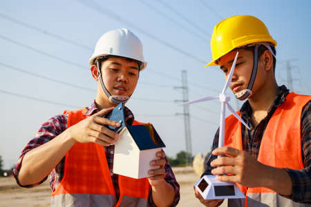 Asian engineer, foreman or leader discussion about home solar cell and wind turbine model in...
