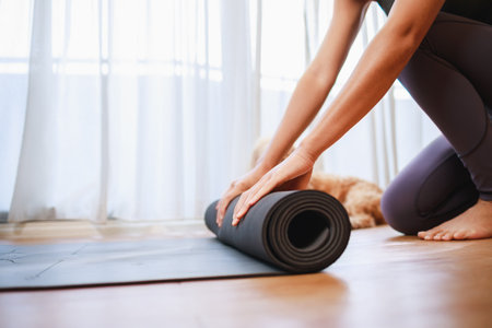 Close-up of woman hands unrolling roll black yoga mat for playing yoga at home for quarantine herself from Covid-19, New normal lifestyle conceptの写真素材
