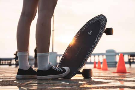 Asian woman leg on surf skate or skate board in outdoor Park at sunset. sport training for trendy people.の写真素材