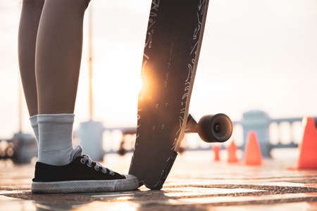 Asian woman leg on surf skate or skate board in outdoor Park at sunset. sport training for trendy people.の写真素材