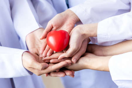 Group of hands holding a red heart. Hand of doctors. donate and insurance, insurance health care, love, family insurance, and CSR conceptの写真素材