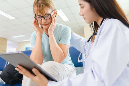 female doctor gives advice to the old woman patient through a tablet at the hospital.の写真素材