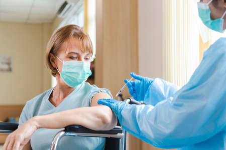 elderly woman patient getting covid-19 or coronavirus vaccine in a wheelchair âat the hospital.の写真素材