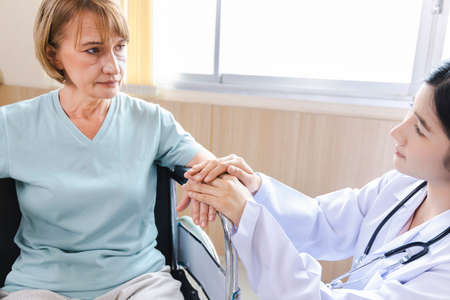 female doctor gives advice and encourages the old woman patient in a wheelchair âat the hospital.の写真素材