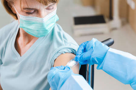 elderly woman patient getting virus vaccine in a wheelchair âat the hospital.の写真素材