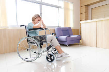old woman patient in a wheelchair is discouraged and alone.の写真素材
