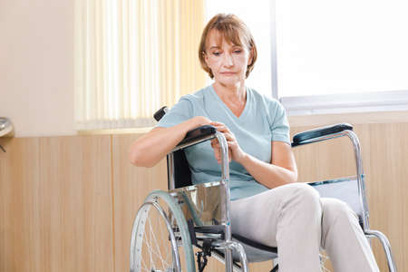 old woman patient in a wheelchair is discouraged and alone.の写真素材