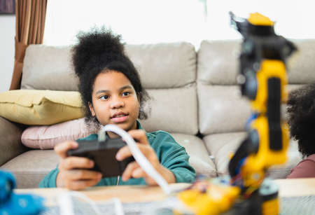 Two African American girls learned robot arms with a program computer. Innovative technology mechanical for Assistive Technologyの素材 [FY310177296574]