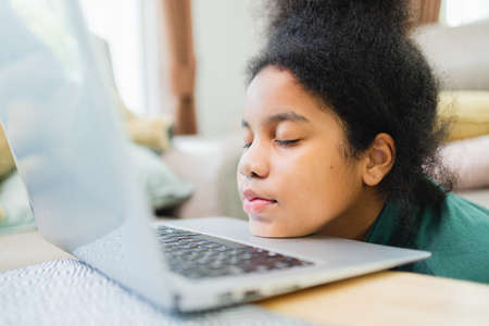 Lazy African American girl with the computer before studying online at home.の写真素材