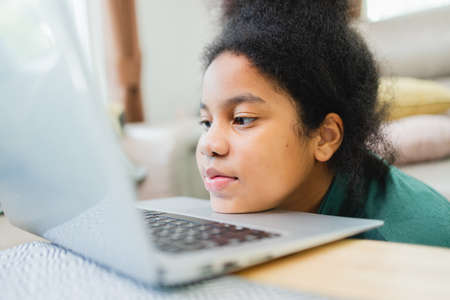 Lazy African American girl with the computer before studying online at home.の写真素材