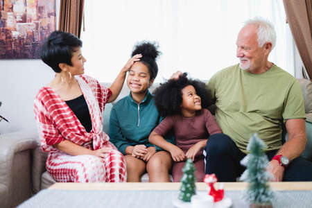 Happy family have fun sitting together on the sofa at home. cheerful young family with children laughing. African American familyの写真素材