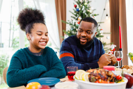 African American family. Merry Christmas. Happy family are having dinner at home. Celebration holiday and togetherness near Christmas tree.の写真素材
